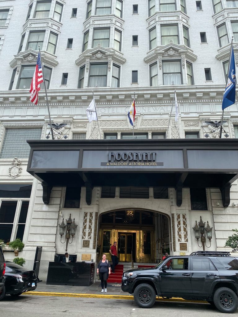 "Elegant exterior of The Roosevelt Hotel in New Orleans, showcasing its historic architecture with grand windows and classic detailing, surrounded by a vibrant city atmosphere."