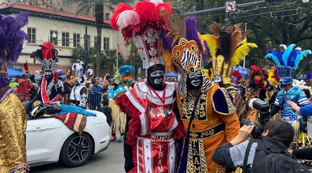 "Participants at the Zulu Parade in New Orleans dressed in vibrant, elaborate costumes featuring feathers, beads, and bold colors, capturing the essence of Mardi Gras celebrations."