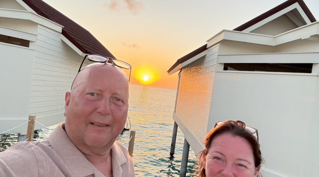 “Water villa at sunset with golden sunlight reflecting on the calm ocean, creating a tranquil and picturesque tropical scene.”